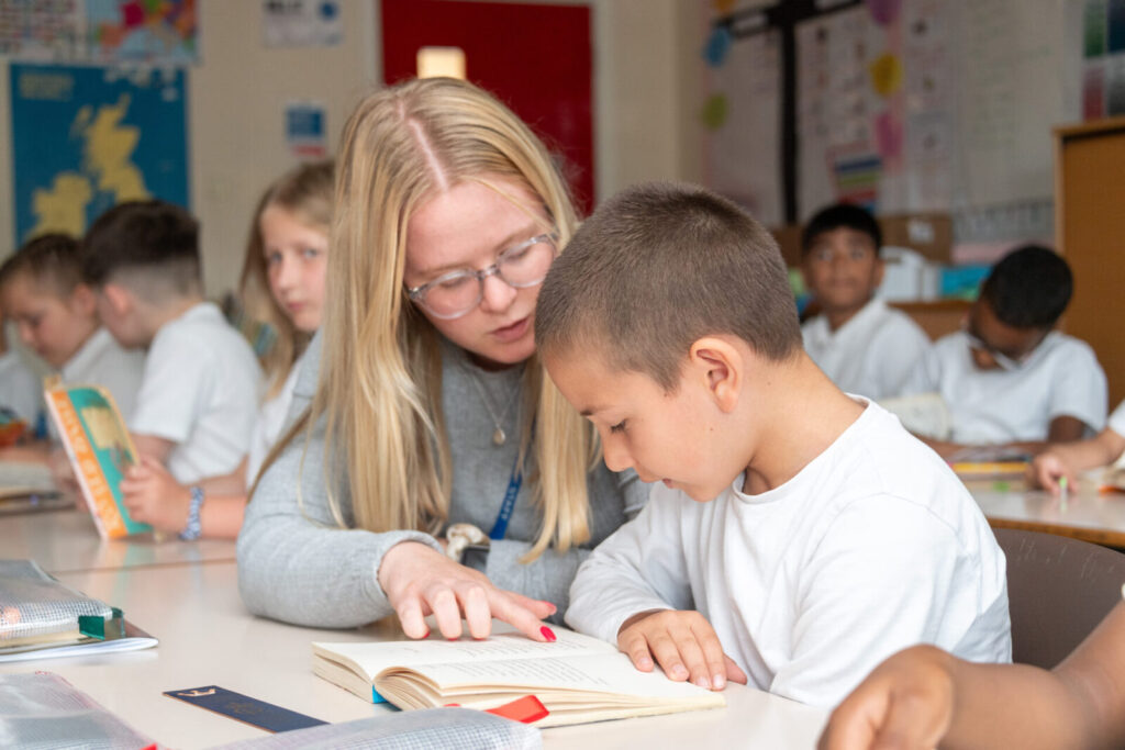 a picture of a teacher helping a student read