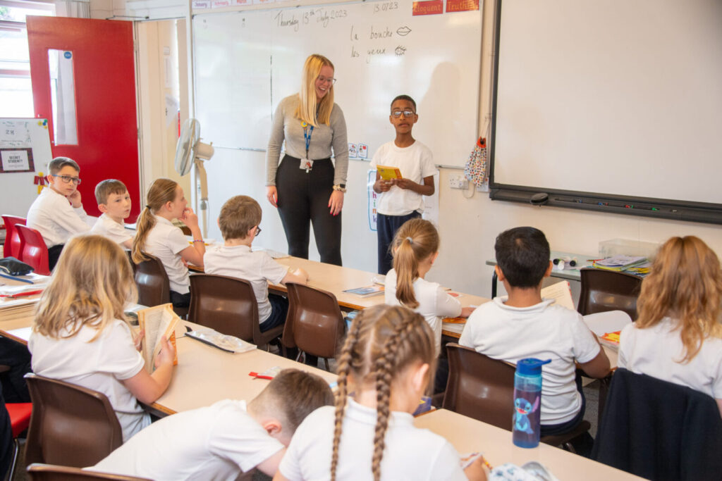 a picture of a teacher helping a student read to the class