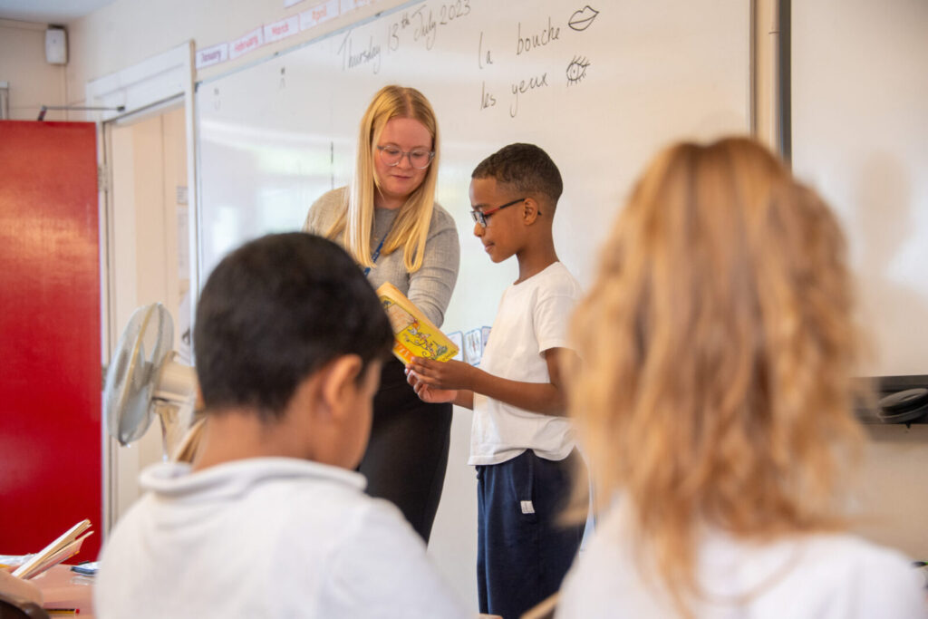a picture of a teacher helping a student read to the class